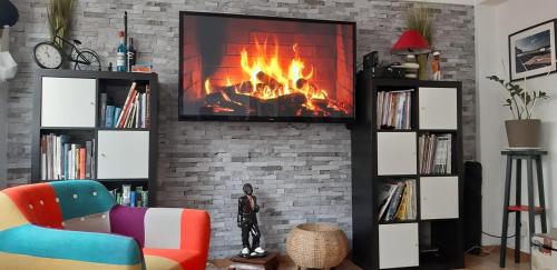 a living room with a fireplace with a tv on a brick wall at sur ile du pollet in Dieppe