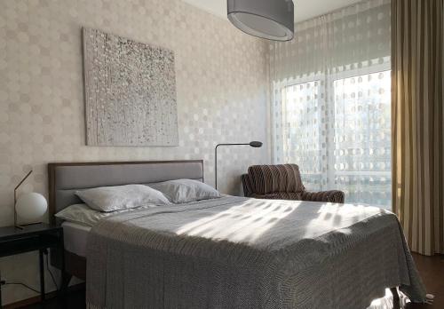 ein Schlafzimmer mit einem Bett, einem Stuhl und einer Lampe in der Unterkunft Sunset Residence - 5 min to the beach! in Narva-Jõesuu