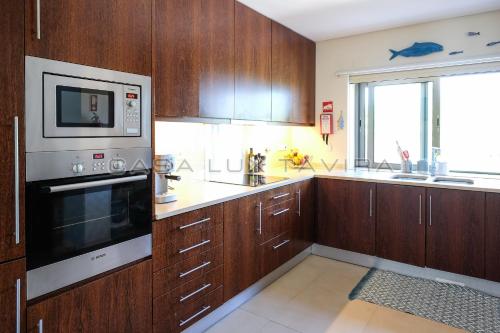 una cucina con armadi in legno e forno a microonde di Casa Lux Tavira a Luz de Tavira