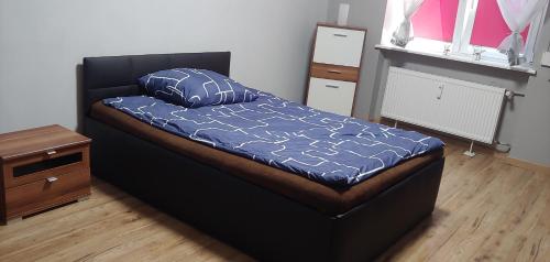 a bedroom with a bed with a blue comforter at Mazur in Kalisz