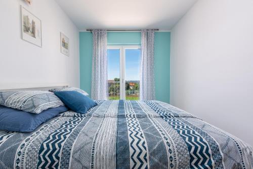 sypialnia z łóżkiem i dużym oknem w obiekcie R&B Family Apartments w mieście Sveti Filip i Jakov
