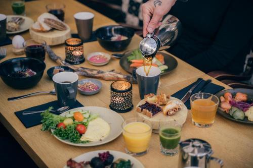 a table topped with plates of food and a person pouring juice at Lapland Hotels Tampere in Tampere