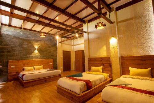 two beds in a room with wooden floors and ceilings at Peaceful Cottage & Cafe Du Mont in Nagarkot