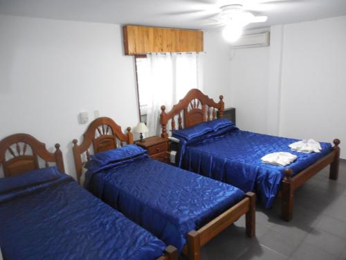 a room with three beds with blue sheets at Victor Hotel in Villa Carlos Paz