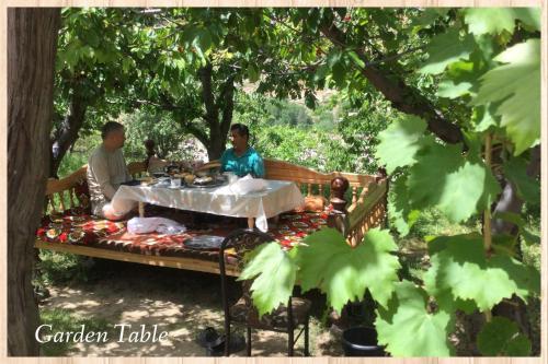 a man and woman sitting on a bench under a tree at Spring Family Guest House in Tersak