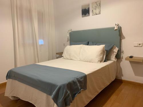 a bed with a blue headboard in a room at NOVO Apartahotel & Restaurante in Las Cabezas de San Juan