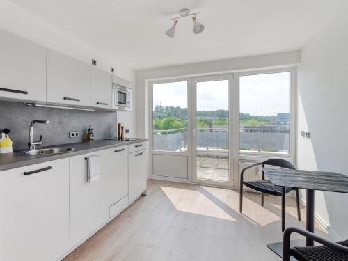 a kitchen with white cabinets and a table and a window at Limehome Wolfsburg Porschestraße in Wolfsburg