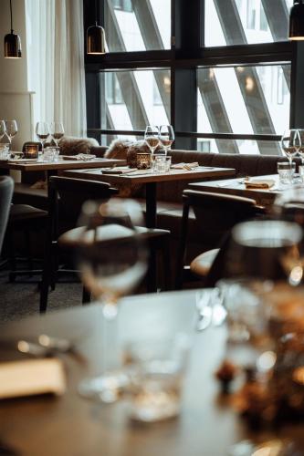 a restaurant with wooden tables and chairs and windows at Lapland Hotels Arena in Tampere