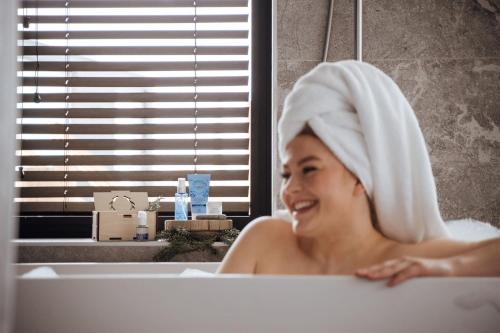 a woman in a bath tub with a towel on her head at Lapland Hotels Arena in Tampere