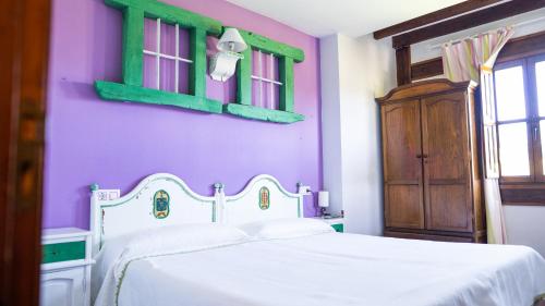 a bedroom with a white bed and a purple wall at Fuente De Las Anjanas in Estrada