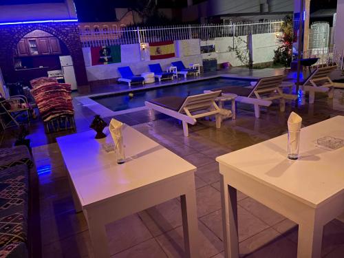 Luxor Oasis Guest House في الأقصر: طاولتين وكراسي في غرفة مع مسبح