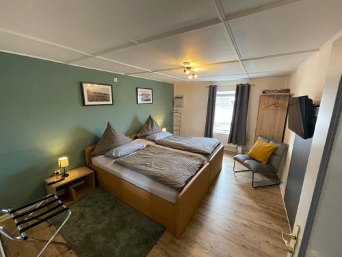 a bedroom with a bed and a chair in it at Eifel Quartier Pension und Gasthof "Em Gardestüffje" in Mechernich