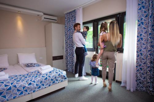 a family standing in a hotel room looking out the window at Hotel Danica in Vrnjačka Banja