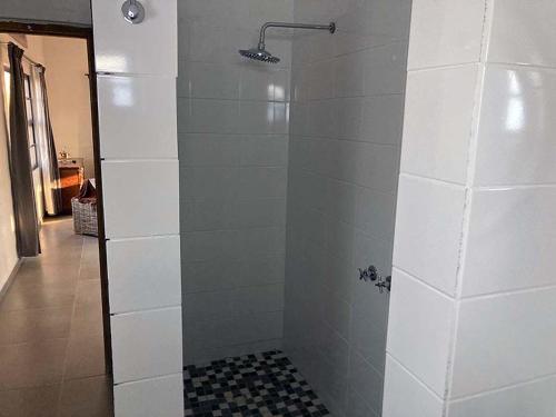 a shower in a bathroom with a white wall at 3 ALOES GUESTHOUSE in Uis