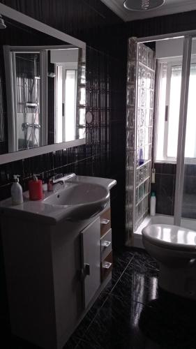 a bathroom with a sink and a toilet and a mirror at Piso centrico en Pravia, con 3 habitaciones sin ascensor in Pravia