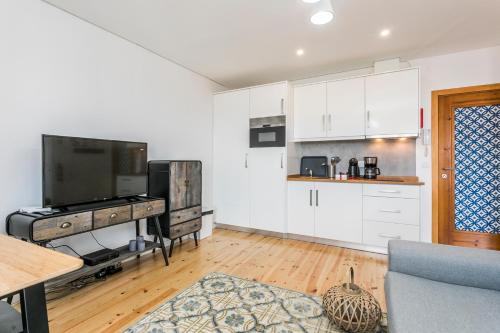 uma cozinha com armários brancos e uma televisão num quarto em Santo Estevão by SpotOn Apartments em Lisboa