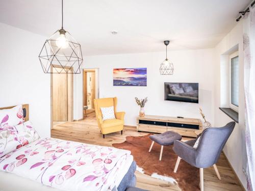 a bedroom with a bed and two chairs and a tv at Apartments Frauensee in Reutte