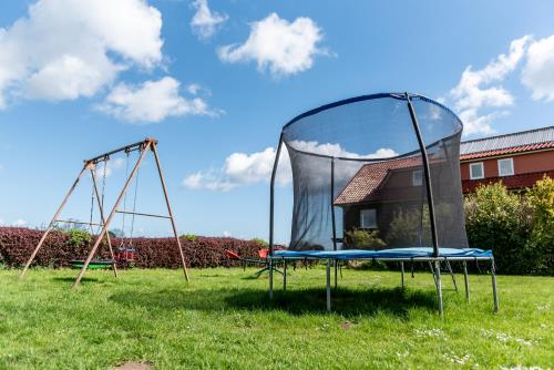 a playground with two swings in a field at Strandperle Appartements in Hasselberg
