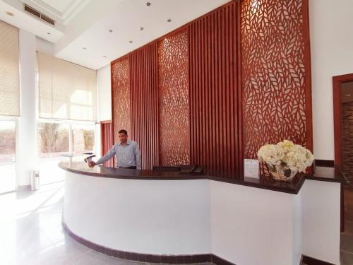 a man standing at a bar in a hotel lobby at Vai by Romance Hotel & Aqua Park in Ain Sokhna