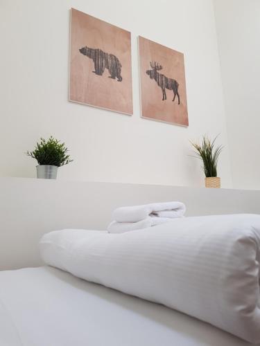 a white bedroom with a bed with two pictures on the wall at Chata Kvilda in Kvilda