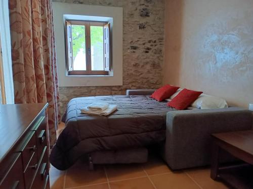 a bedroom with a bed and a couch and a window at Casa sala pinta in Castellfort