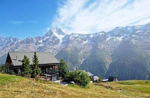 a house on a hill with mountains in the background at Lauchernalp Resort Residences in Wiler
