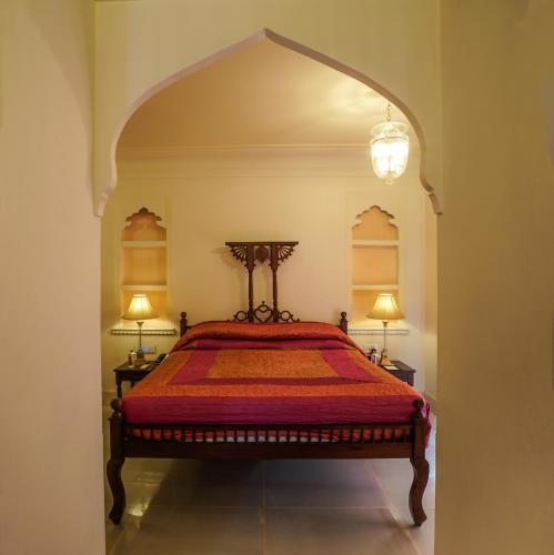 a bedroom with a red bed with two lamps at Shahpura House in Jaipur