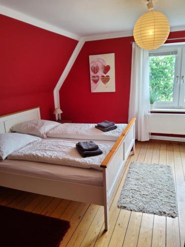 ein Schlafzimmer mit einem Bett mit einer roten Wand in der Unterkunft Ferienhof und Reittherapie Deichwind - Nordfriesland - 2 Häuser in Hattstedtermarsch