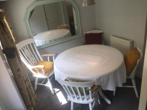 een tafel en stoelen in een kamer met een spiegel bij Cricketers Cottage B&B in Kent