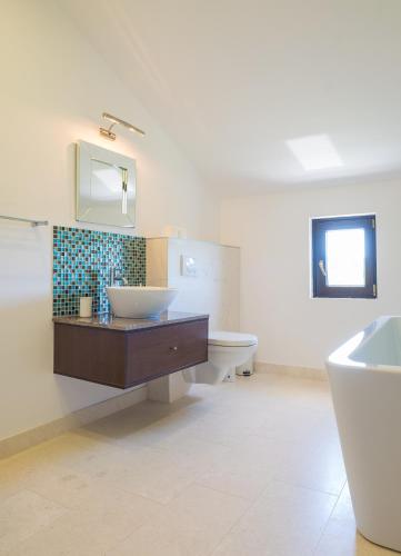 a bathroom with a sink and a toilet and a mirror at Villa Lustica in Lustica