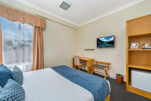 a hotel room with a bed and a desk at Ramada by Wyndham, Hamilton City Center in Hamilton