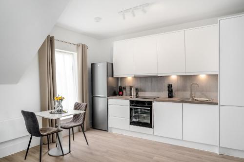 a kitchen with white cabinets and a table and chairs at Citystay Living - Finch House in Cambridge