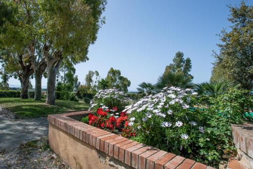 a garden with red and white flowers in a retaining wall at Appartamento Giannutri in Riotorto