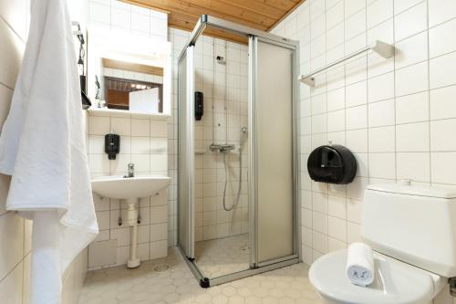 a bathroom with a shower and a toilet and a sink at Hotelli Jämsä in Jämsä