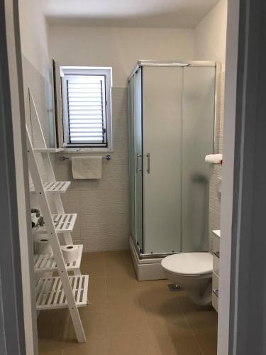 a bathroom with a glass shower and a toilet at Apartmani Silvano in Murter