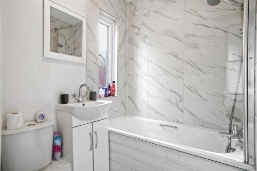 Baño blanco con bañera y lavamanos en Ezy Property Solution Short Lets & Serviced Accommodation Norbury, en Londres