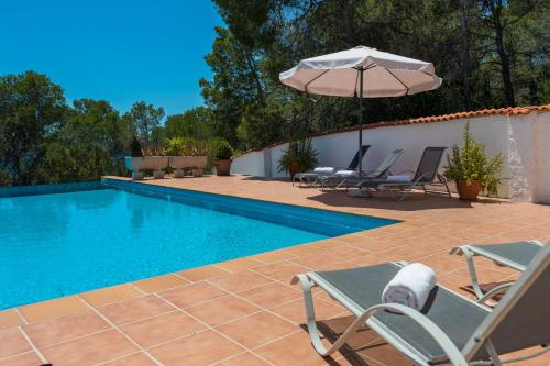 a swimming pool with two chairs and an umbrella at Villa Tres Yucas - La Cabaña in San Antonio