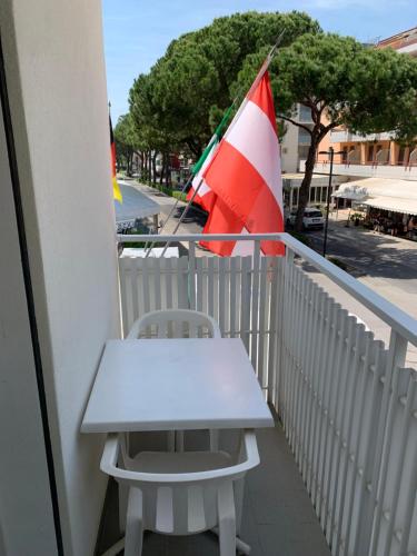 una mesa blanca y una silla en un balcón con bandera en Hotel Al Capitano, en Caorle
