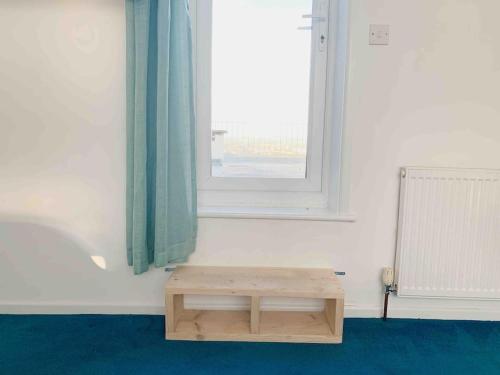 a wooden bench in a room with a window at Shan Mu Inn Entire flat 2 bedrooms with terrace seaview BBQ in Newlyn