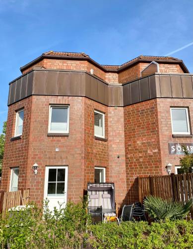 a red brick building with a black roof at Ferienwohnung Gustav - Moderne Maisonette-Wohnung mit Terrasse in Wangerooge