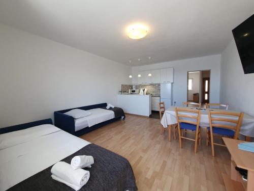 a bedroom with a bed and a table and a kitchen at Apartmani Silvano in Murter