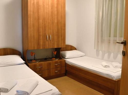 a room with two beds and a wooden cabinet at Apartmani Obala in Promajna