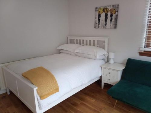 a bedroom with a white bed and a green couch at Glen Nevis Place in Inverlochy