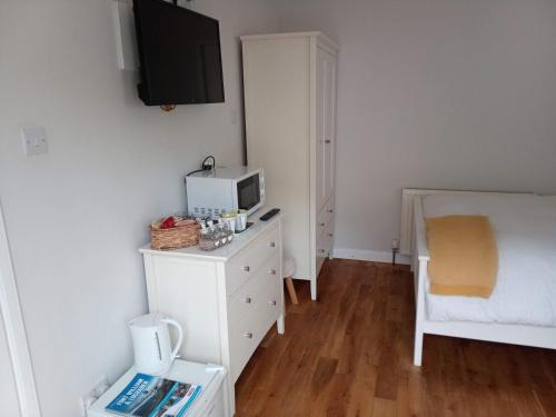 a bedroom with a white dresser with a tv on the wall at Glen Nevis Place in Inverlochy