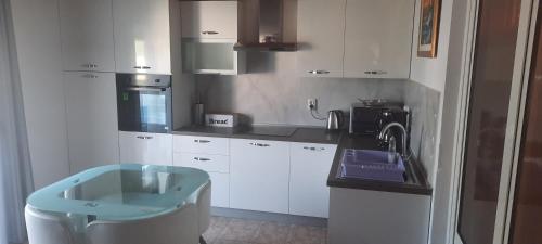 a kitchen with white cabinets and a blue sink at Apartmani Premijer-Rab in Supetarska Draga