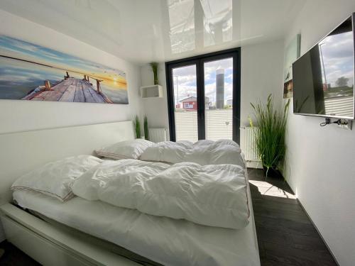 1 dormitorio con 1 cama blanca y una pintura en la pared en Hausboot Ferienhaus Captains Boat, en Kappeln