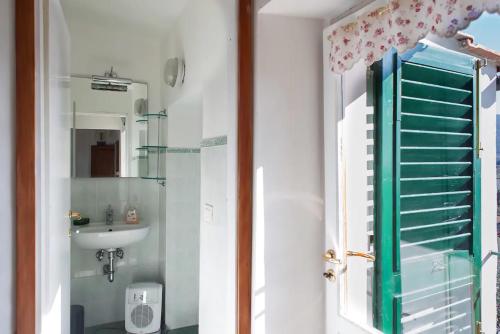 a bathroom with a sink and a green shutter at Appartamenti Tortorella in Pelago