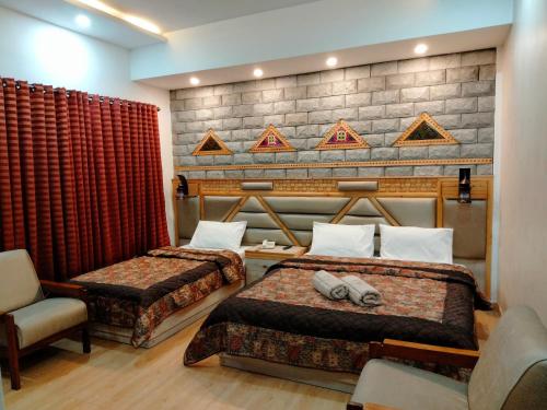 a hotel room with two beds and a chair at Park Hotel Gilgit in Gilgit