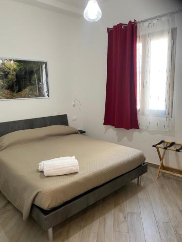 a bedroom with a bed with a red curtain at DOMOBLU Camere In Centro in Tortolì