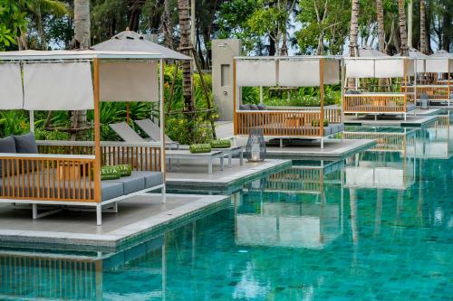 a pool at a resort with chairs and umbrellas at Meliá Phuket Mai Khao in Mai Khao Beach